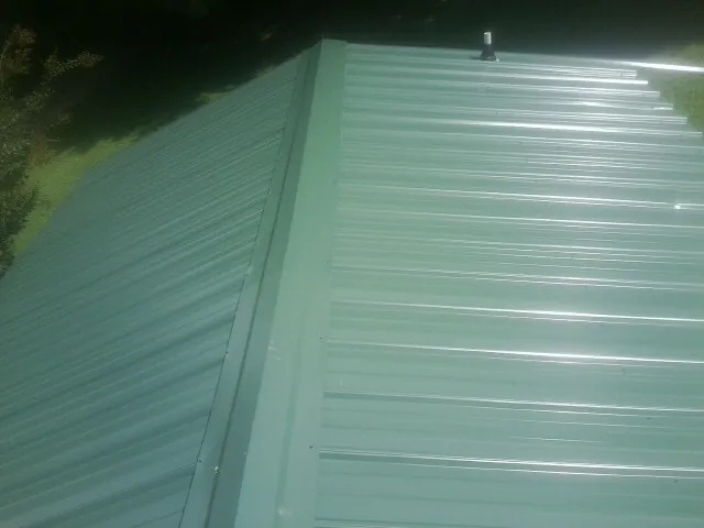 New green metal panels meeting at the ridge of a roof — Flat Roof Repair work by our crew in Banks