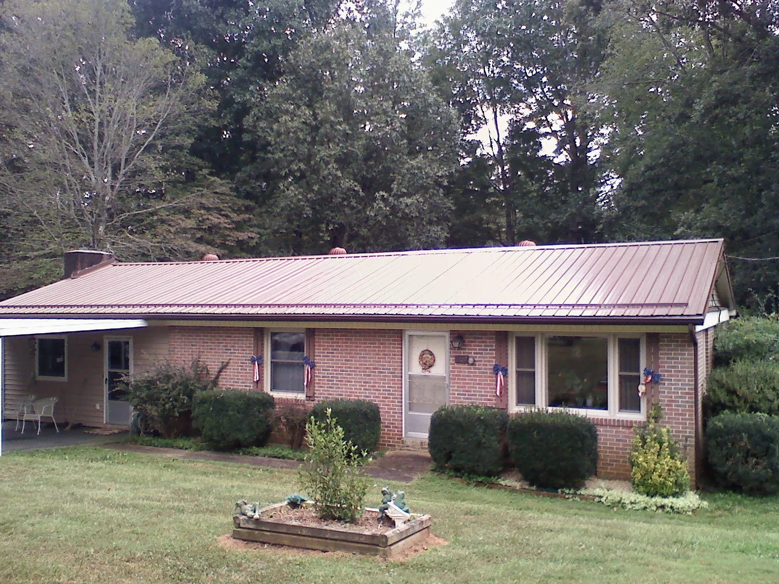 Bronze metal roof on a brick ranch home with a carport in Banks
