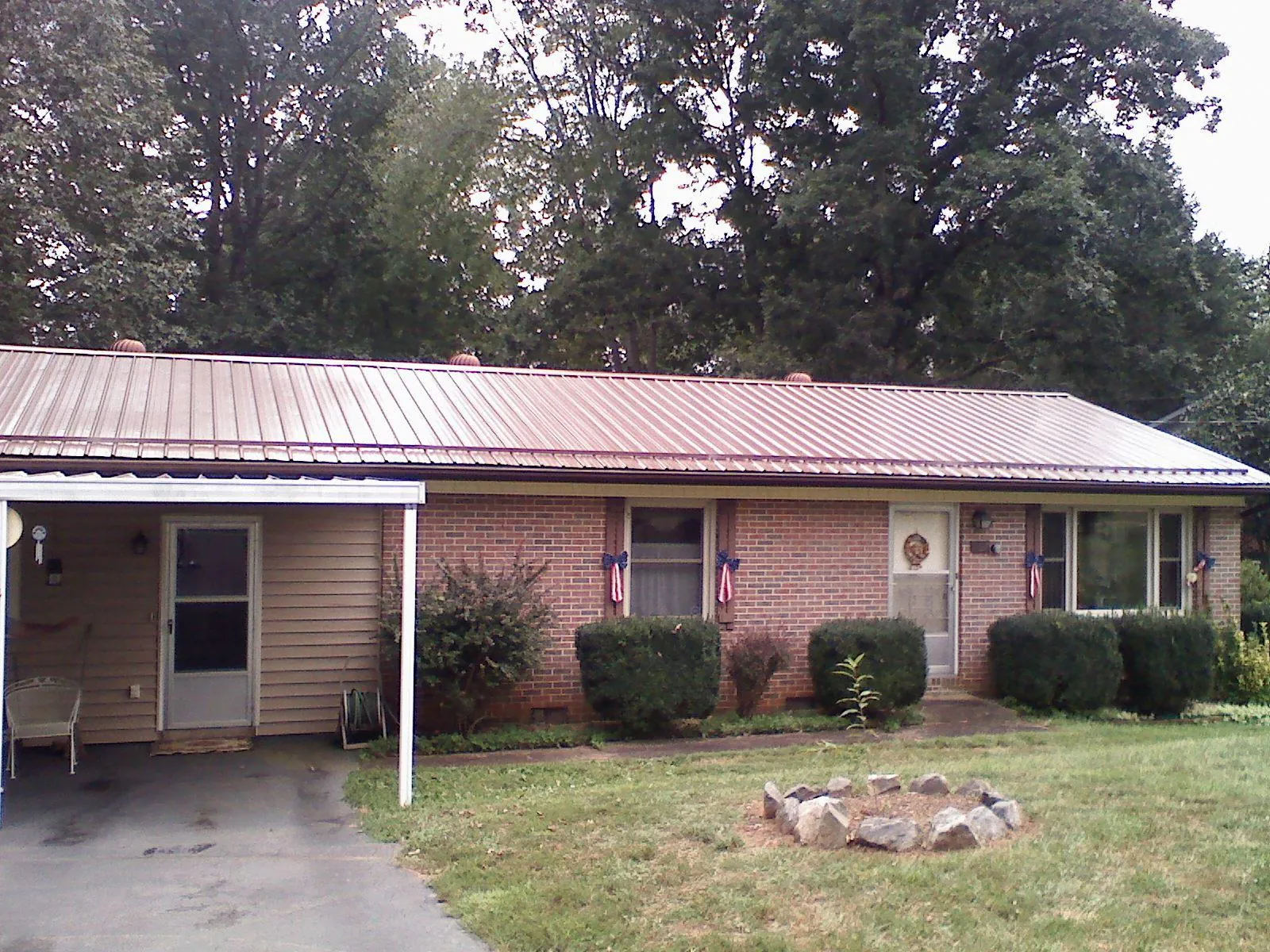 Bronze metal roof and carport on a brick ranch home — Roof Repair work by our crew in Banks