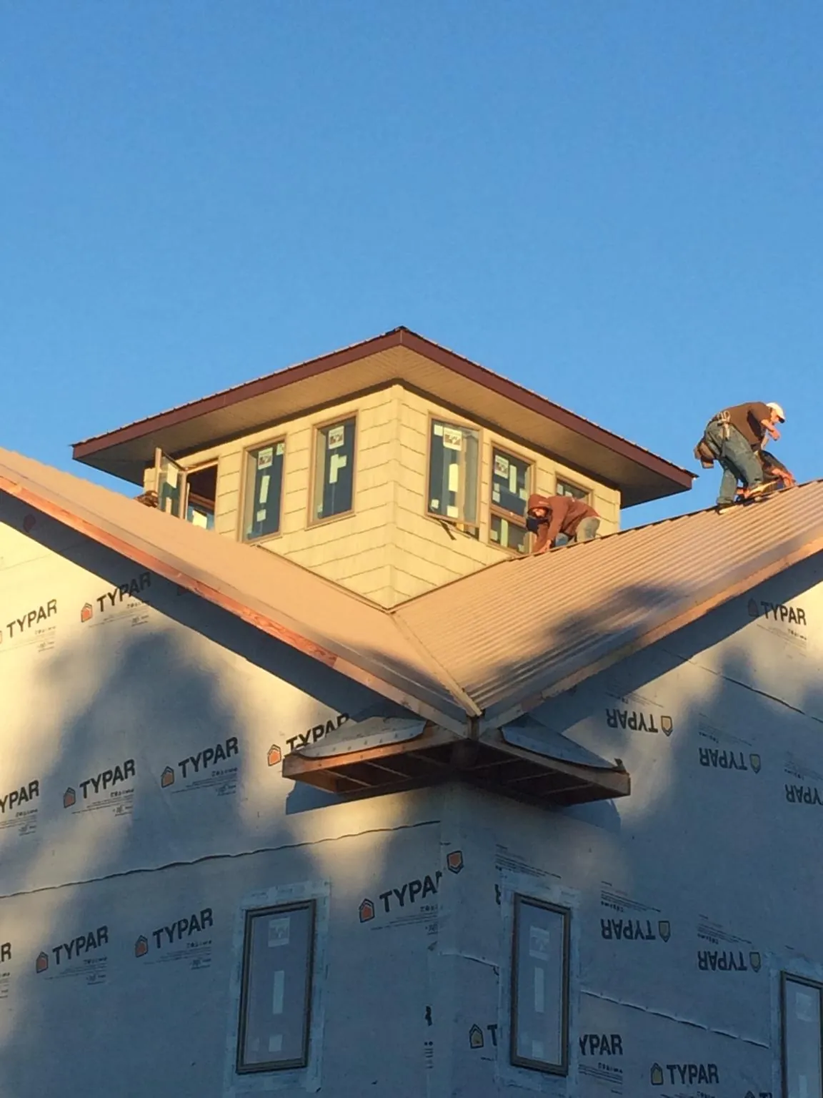 Roofers working around a rooftop cupola on a new metal roof at sunset — Roof Waterproofing in Banks by Roofing Brothers